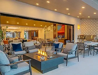 view of an indoor and outdoor living room space with a fire pit and menorah on the edge of the fire pit