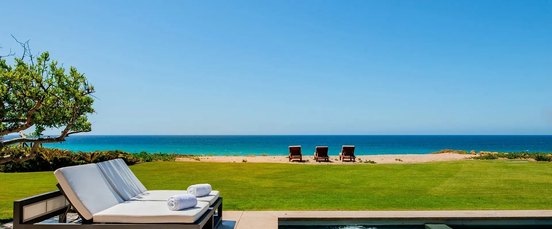 Ocean side luxury villa with two lounge chairs next to an infinity pool