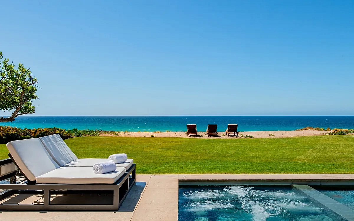 Ocean side luxury villa with two lounge chairs next to an infinity pool